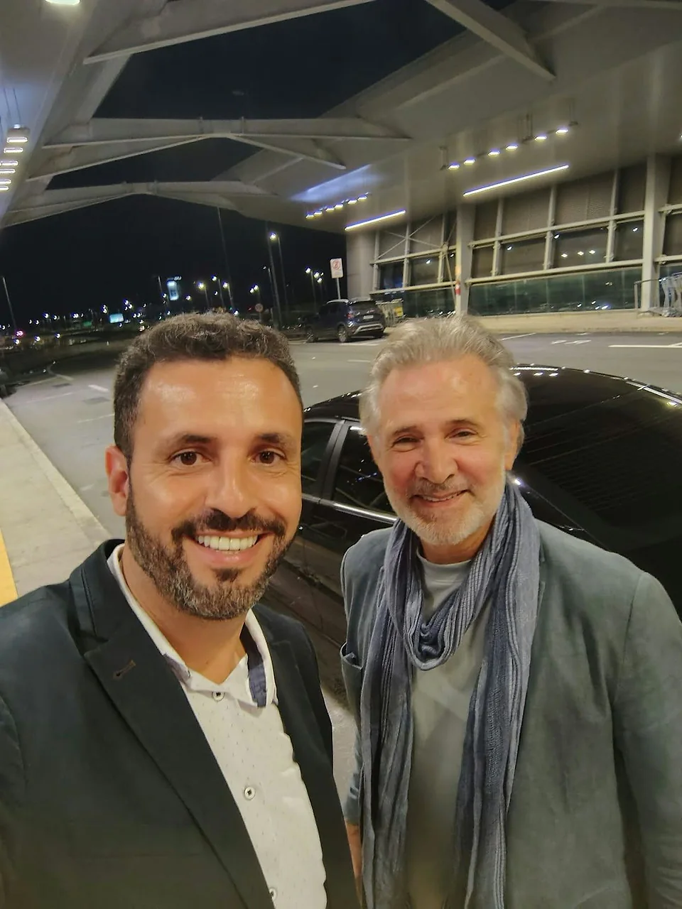 Cliente recebido pelo motorista da TEVO no Aeroporto de Confins, ao lado do carro executivo